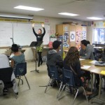 Lorelei with armsraised speaking to a group of students 