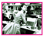 black and white photo of a Lorelei wearing a ball gown, putting on earrings in front of a dressing table