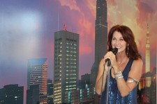 Host Emcee Lorelei Shellist holding microphone, Los Angeles backdrop